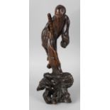 A 19th century Chinese rootwood carving, modelled as an immortal, standing upon a base of