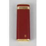 A Cartier lighter of oblong form, the red lacquer body with gold coloured twist band, marker Cartier