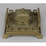 A late 19th century brass inkwell, the hinged cover enclosing glass liner, upon a base with 'Gothic'