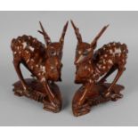 A pair of early 20th century Chinese carved hardwood deer, each raised upon shaped and carved bases,