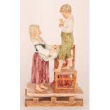 A large late 19th Century continental figurine modelled as a young boy stood on a chair with a