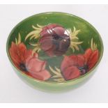 A large Moorcroft Anemone pattern footed bowl decorated with tubelined flowers against a green