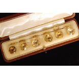 A cased set of six round brilliant cut citrine buttons within a yellow metal mount, unmarked.