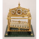 A replica brass Congreve rolling ball clock with three silvered dials above a platform supported by