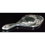 An Art Nouveau silver backed hand mirror of quatrefoil outline with embossed flower heads amidst