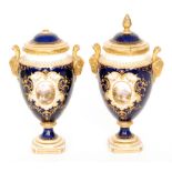 A pair of early 20th Century Coalport pedestal vases each decorated with hand painted landscape