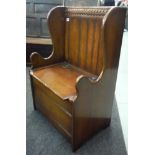 A small 17th Century style oak box seat settle with high carved panelled back and shaped ends,