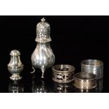 A Danish silver sugar caster, three hallmarked silver circular napkin rings and a small pepper pot,