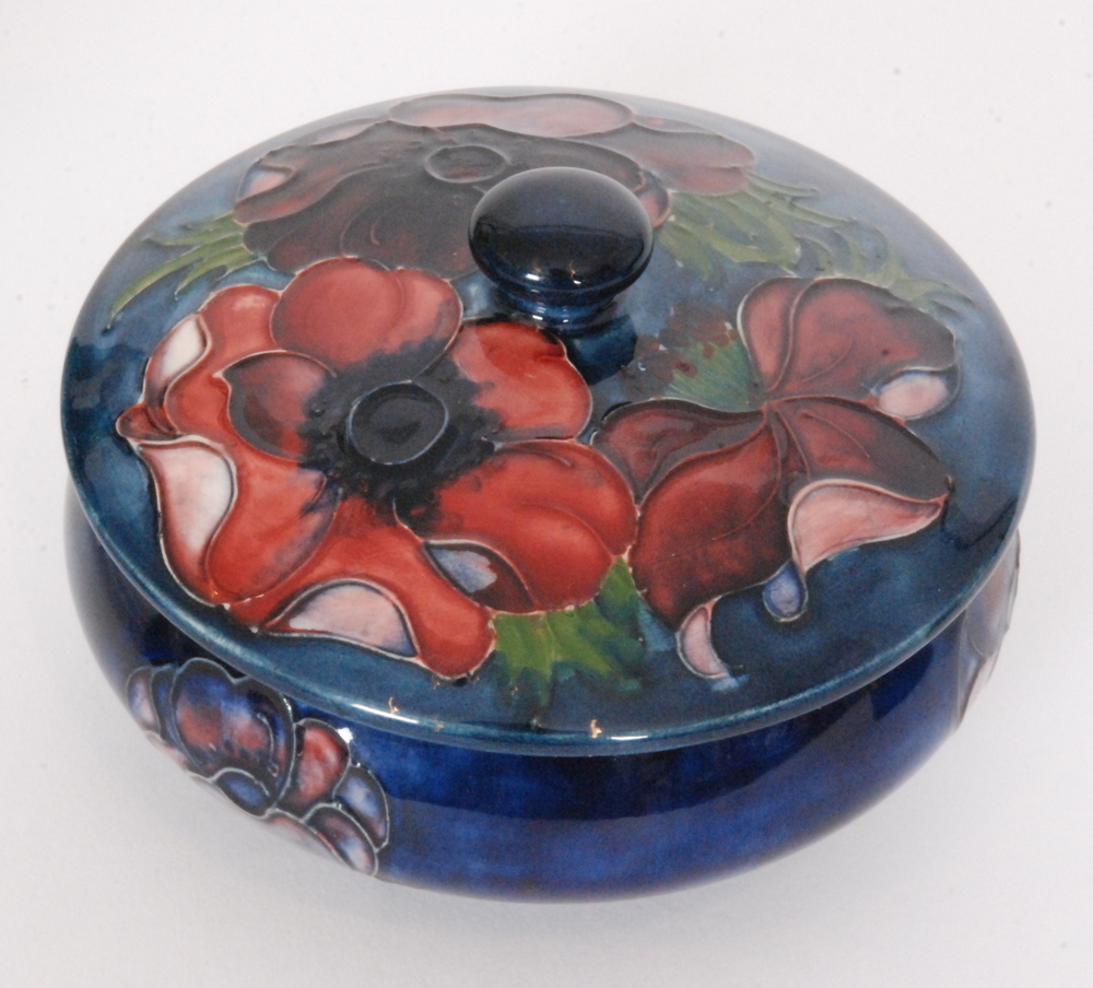A Moorcroft Anemone pattern powder box and cover decorated with tubelined flowers against a dark