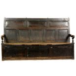 An 18th Century oak settle with a fielded five panel back above a later elm seat and a triple