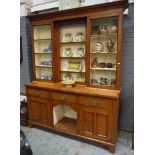 A late 19th Century light oak dresser with inverted glazed cupboard rack over a base fitted with