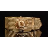 A 1960s hallmarked 9ct strap bracelet, the brick link strap with looped ribbon tied buckle,