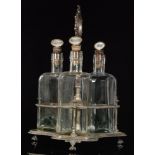 An early 20th Century tantalus with three square glass bottles all with cork stoppers with spirit