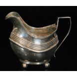 A George III hallmarked silver cream jug of cushion form with reeded border,