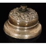 An early 20th Century hallmarked silver desk bell with embossed foliate decoration surround central