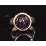 A Danish Sterling silver and amethyst ring, the circular cabochon amethyst collar set to plain band,