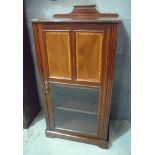 An Edwardian satinwood banded mahogany music cabinet enclosed by a pair of panels and glazed door