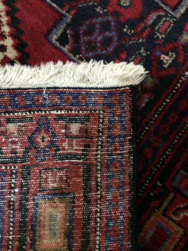 A Middle Eastern woollen rug, with three geometric motifs to the central red field, - Image 2 of 2