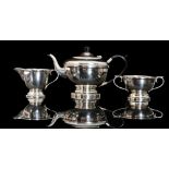 A hallmarked silver three piece pedestal tea set of circular plain form each piece with foliate
