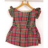 A 19th Century child's dress in pink tartan with green velvet trim and brass buttons,