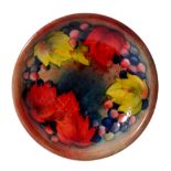 A William Moorcroft shallow circular dish decorated in the flambe Leaf and Berry pattern,