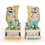 A pair of Chinese brightly coloured spill vases modelled as temple dogs raised to a rectangular