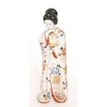 A Japanese model of a Geisha girl standing, dressed in a patterned kimono with gilt detailing,