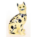 A large Galle style model of a cat glazed in yellow with blue flowers, retains green glass eyes,