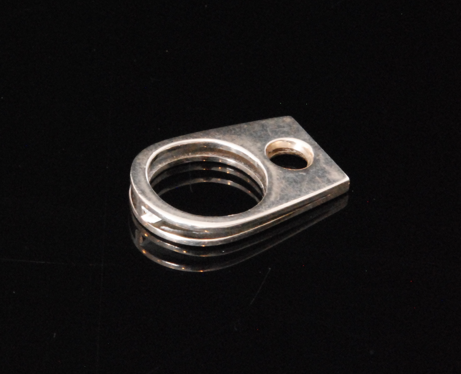 A modernist silver abstract ring with split shank and tapering flat head detailed with central