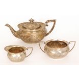 A hallmarked silver three piece boat shaped teaset with part fluted decoration, total weight 29oz,
