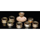 Six hallmarked silver, circular napkin rings, a silver topped rouge pot and an egg cup,