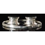 A hallmarked silver double ink well, plain oval base supporting twin well with plain hinged covers,