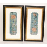 A pair of Chinese framed sleeve panels decorated with flowers and good luck symbols on a blue
