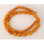 A single row of amber beads composed of forty four opaque to semi translucent oval shaped beads of