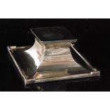 A hallmarked silver square ink well with raised borders and swept body below plain square cover,