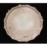 A hallmarked silver circular salver of plain form with beaded border raised on three claw and ball