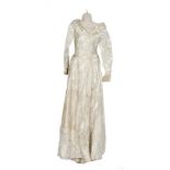 A 1950s vintage wedding dress in an ivory brocade fabric with a faint gold pattern and bow detail