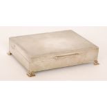 A hallmarked silver engine turned cigarette box of rectangular outline on four bracket feet,