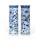 A pair of 19th Century Chinese cylinder vases decorated in blue and white with dragons amidst