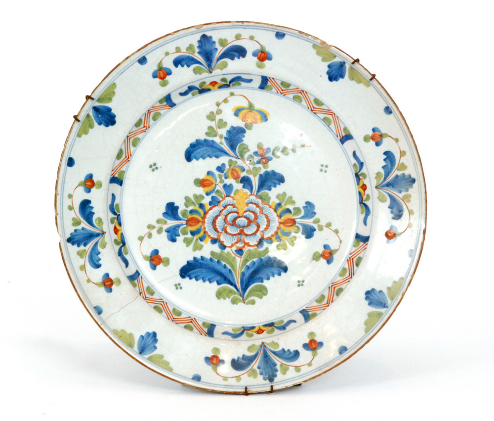 A late 19th to early 20th Century tin glazed charger decorated with a floral spray within a