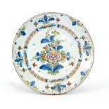 A late 19th to early 20th Century tin glazed charger decorated with a floral spray within a