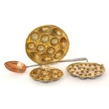 Three circular brass muffin or cake mounds and a copper and iron handled strainer spoon (4)