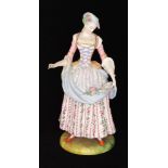 A late 19th Century bisque figure of a lady dressed in a pink bodice and floral skirt,