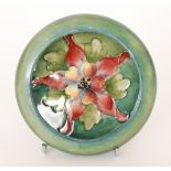 A Moorcroft roll rim pin dish decorated in the Columbine pattern with a central pink flower against