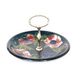 A Moorcroft Anemone pattern cake plate decorated with tubelined flowers against a blue ground,