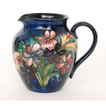 A Moorcroft jug decorated in the Spring Bouquet pattern with a spray of flowers against a blue wash