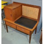 Unknown - A teak telephone table with cane panel back, fitted cupboard and two frieze drawers,