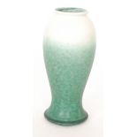 Ruskin Pottery - A vase of footed baluster form decorated in a milk white to tonal green glaze,