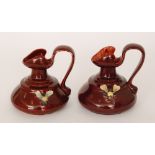 Bretby - A pair of early 20th Century shape 969 jugs each glazed in a dark red with relief moulded