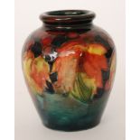 William Moorcroft - A miniature vase of swollen form decorated in the Flambe Leaf and Berry pattern